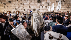 Jewish men carry Torah scrolls as they dance during Simchat Torah celebrations at the Western Wall in Jerusalem Old City