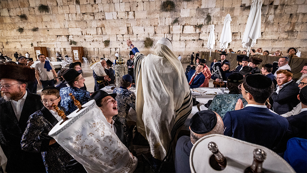 Jewish men carry Torah scrolls as they dance during Simchat Torah celebrations at the Western Wall in Jerusalem Old City